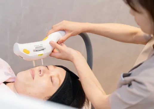 顔に機械でケアをしている