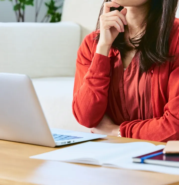 女性がパソコンの前で考えている様子