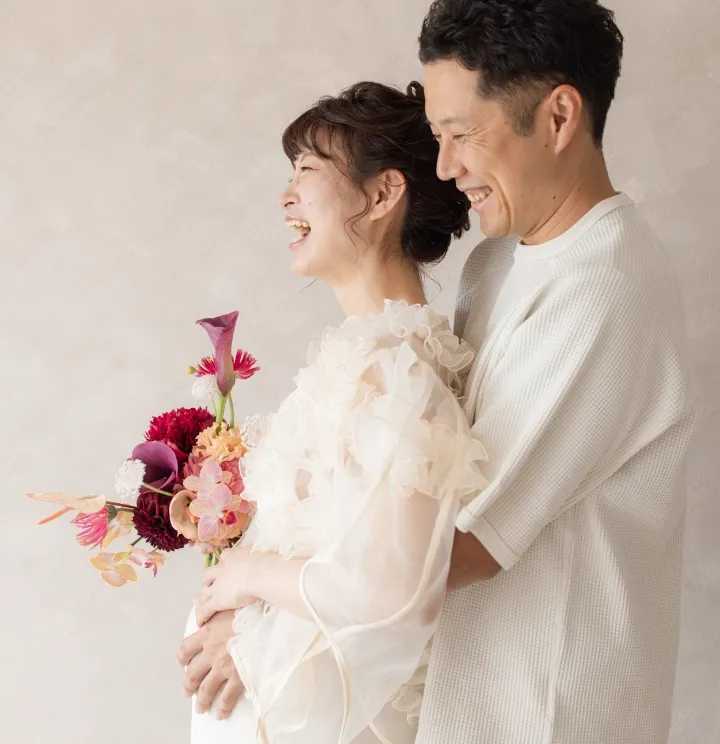 お腹の大きなお母さんをご主人が後ろから抱きしめている様子