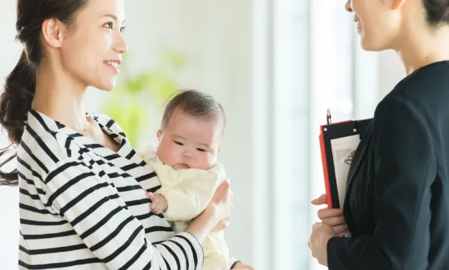 赤ちゃんを抱っこしてお母さんがアドバイスを受けている様子