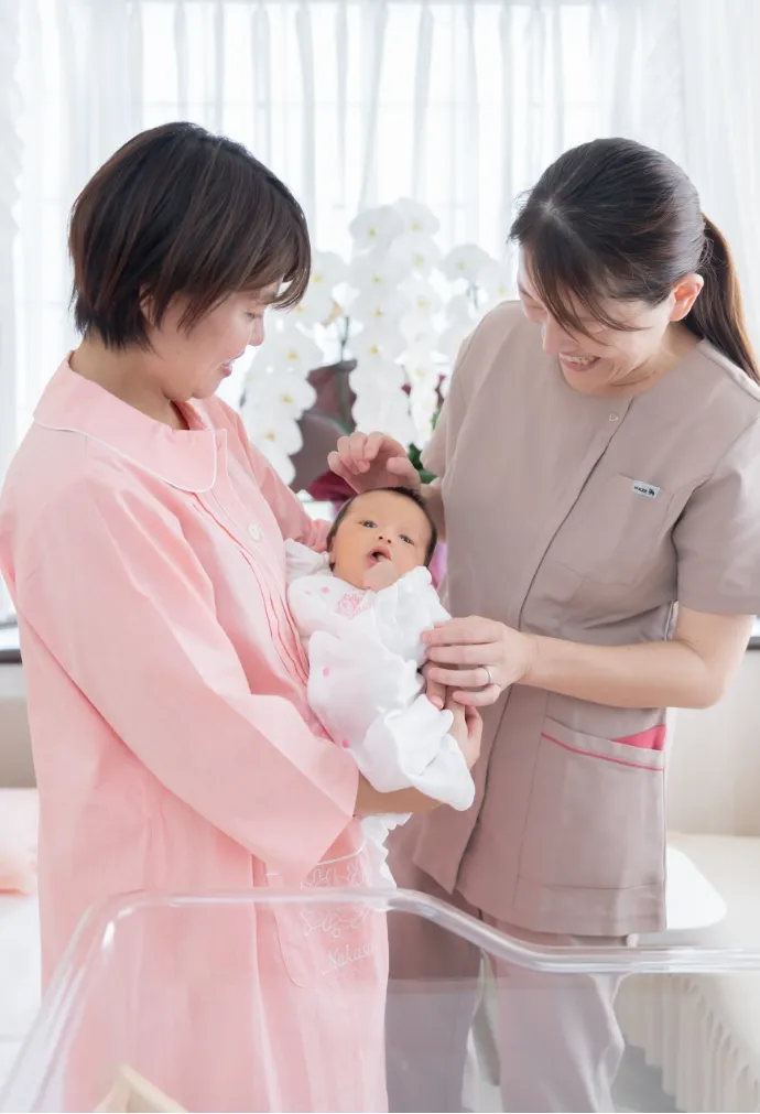 赤ちゃんを抱っこしているお母さんと看護師さん